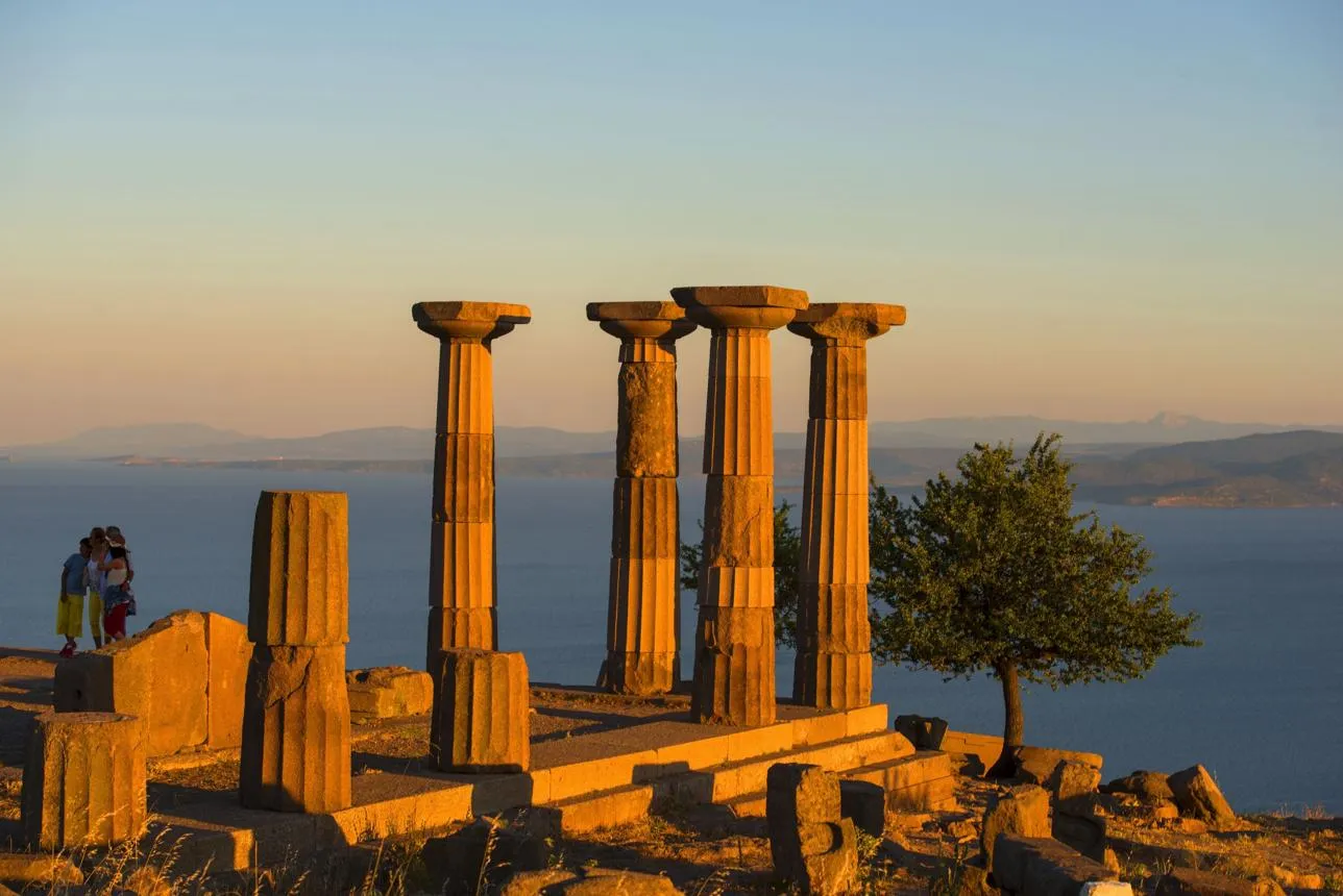 The Doric columns of the Temple of Athena at sunset above the sea, with Lesbos beyond