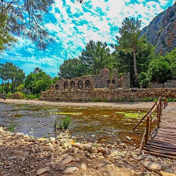 Ruins of Olympos among green trees by a stream