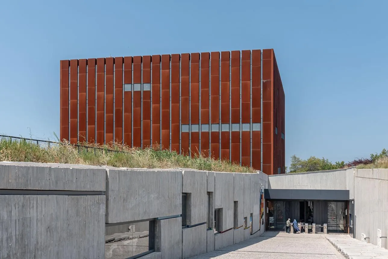 The rust-coloured cube of the Troy Museum above its concrete entrance